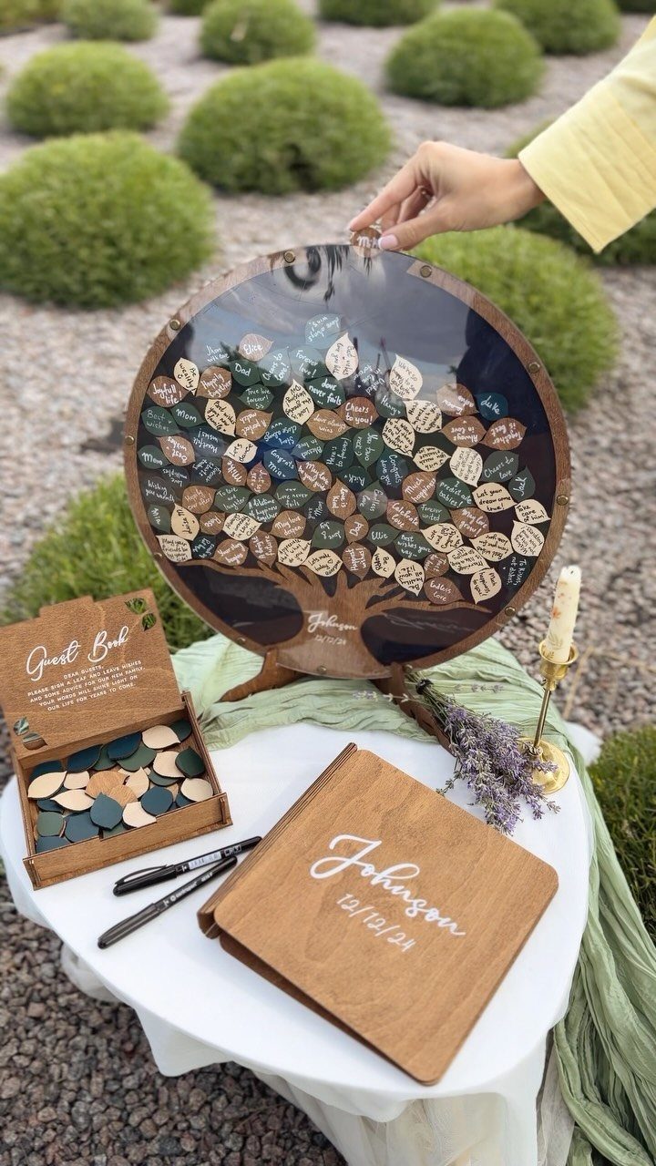 Wooden guest book alternative with a leaf-shaped token tree on a white table.