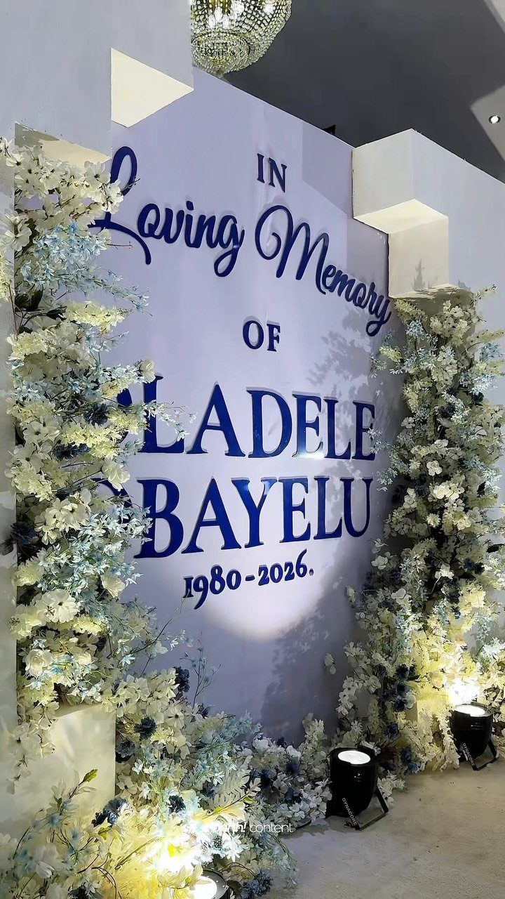 Memorial backdrop with blue text and white floral arrangements for a celebration of life