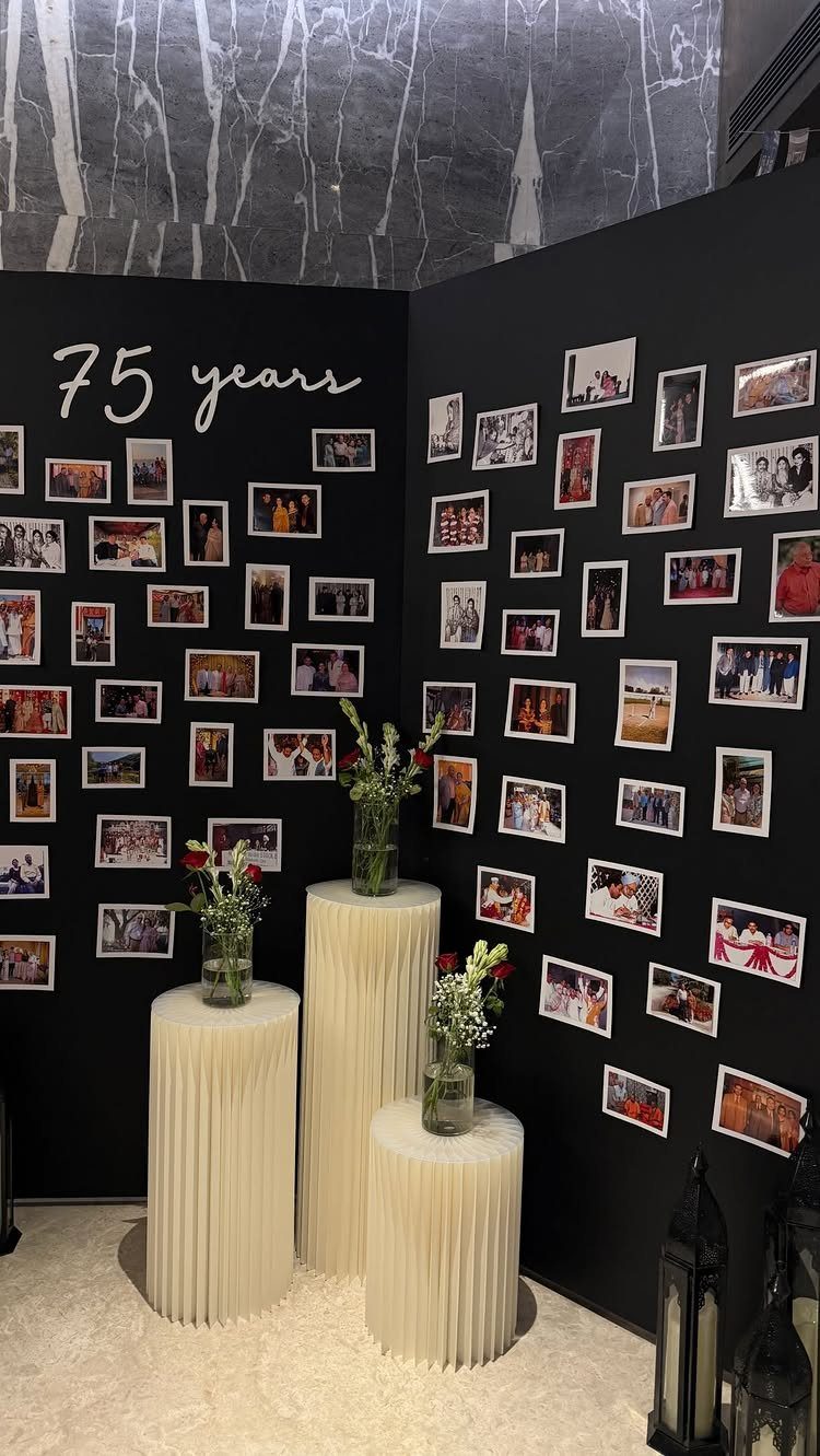Memorial display with photo walls and floral arrangements on white cylindrical pedestals.