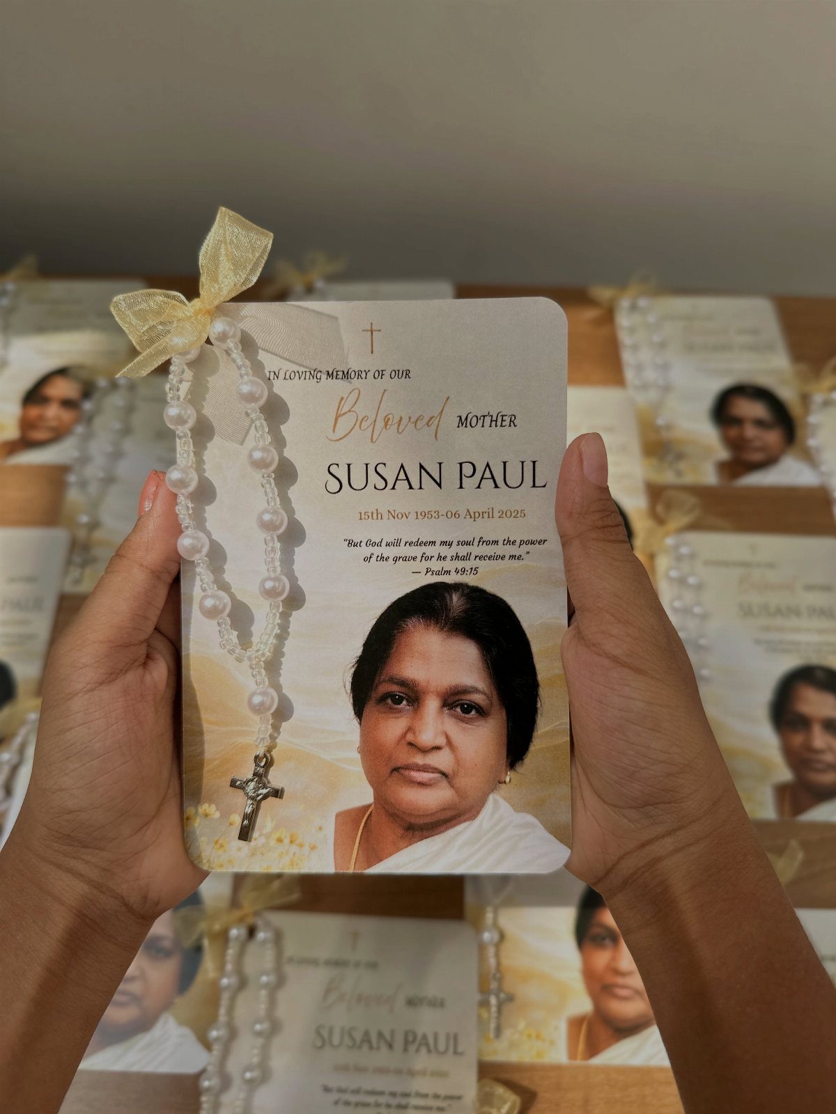 Memorial favor card with a woman's portrait and a white pearl rosary.