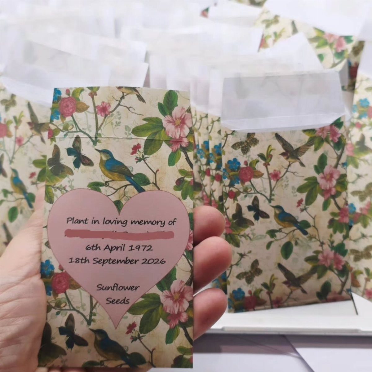 Sunflower seed packets with floral patterns and memorial heart labels for a celebration.