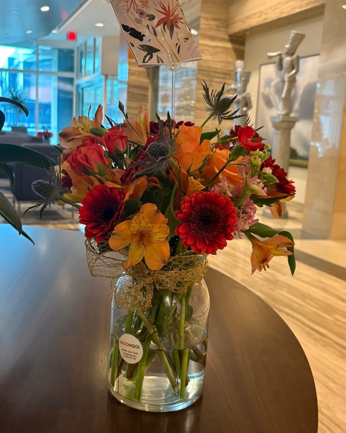 Colorful floral arrangement with red and orange flowers in a glass vase.