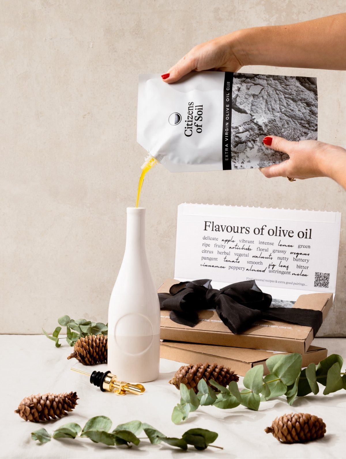Olive oil being poured from a pouch into a white ceramic bottle gift set