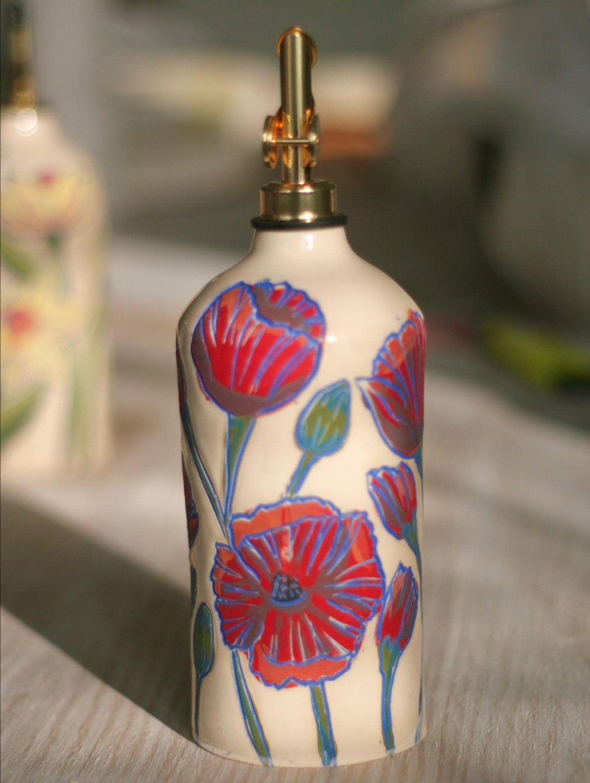 Ceramic bottle with red poppy flower paintings and a gold pump dispenser