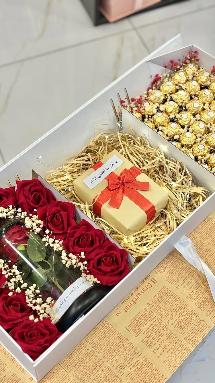 Gift box with red roses, gold chocolates, and a small wrapped present.