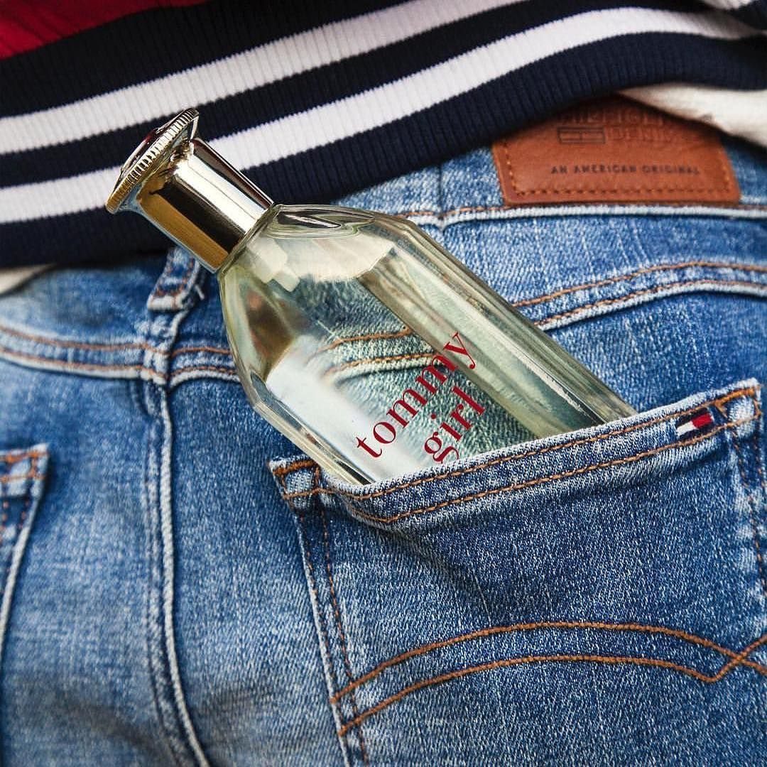 Tommy Girl perfume bottle tucked into the back pocket of blue denim jeans