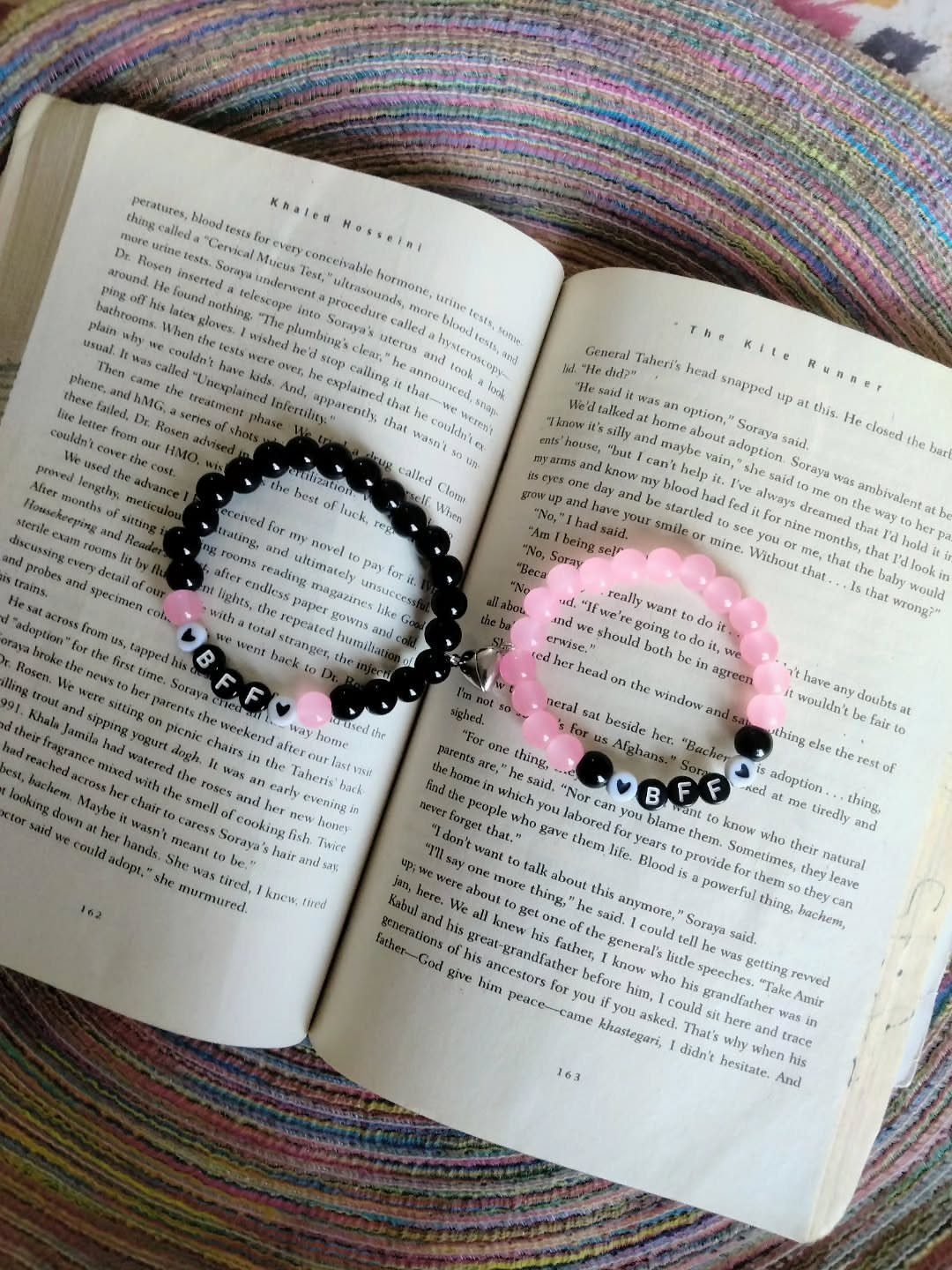 Two beaded BFF friendship bracelets resting on the open pages of a book.
