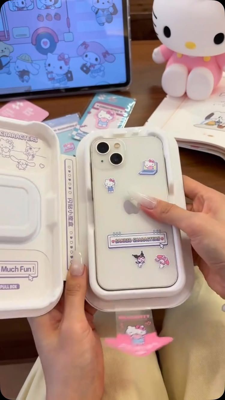 White smartphone with cartoon stickers inside a white gift box held by hands.