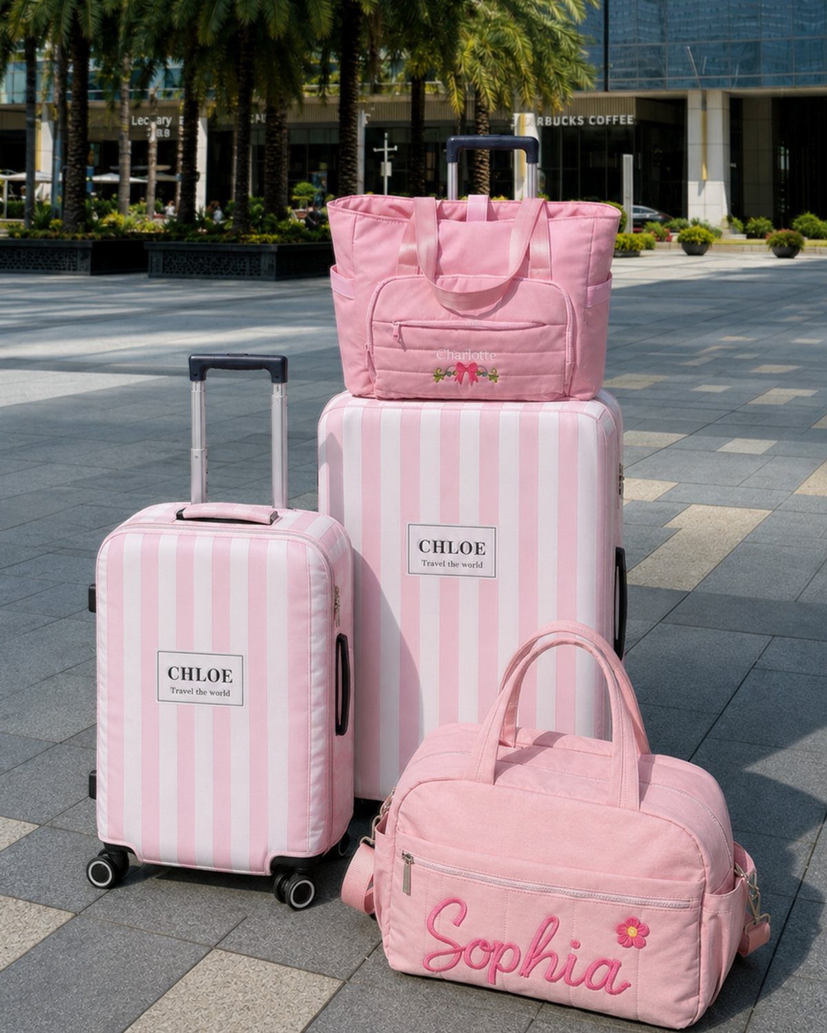 Pink and white striped personalized luggage set on a grey tiled outdoor plaza.
