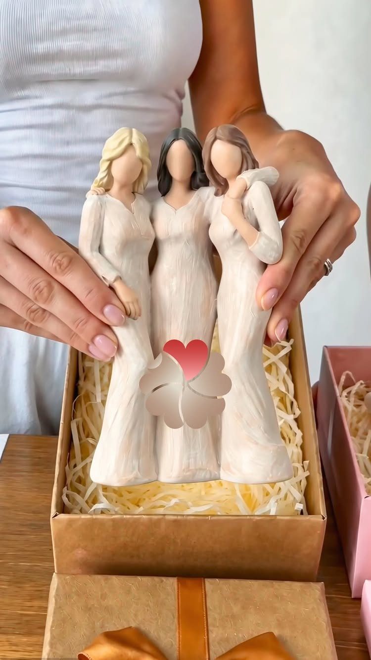 Ceramic figurine of three women embracing with a red heart in a gift box