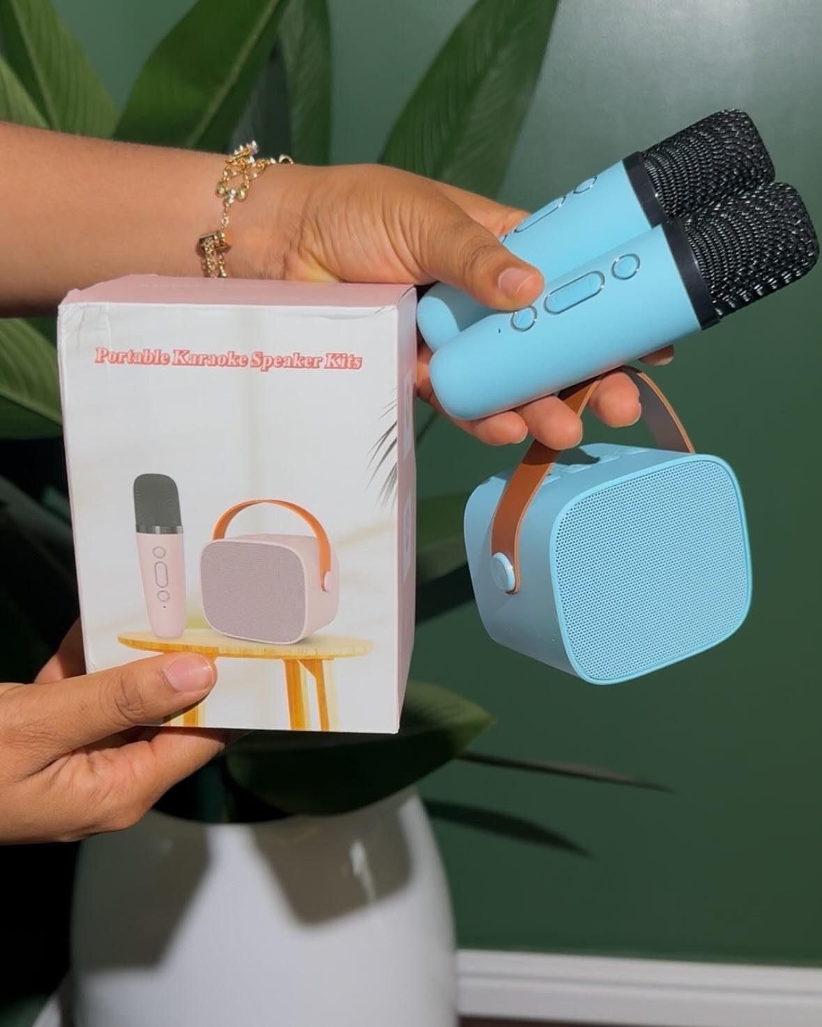 Two light blue mini karaoke microphones and a matching speaker held by hands.