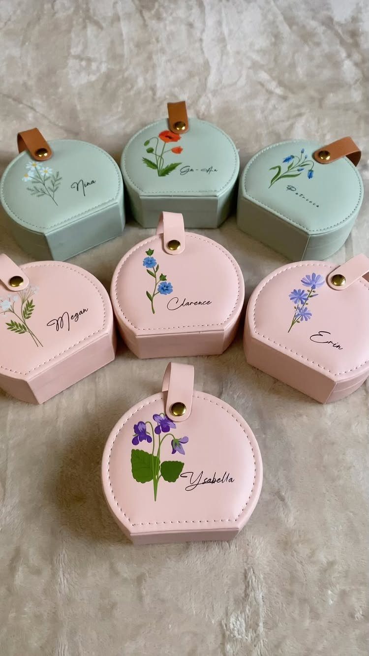 Six personalized hexagonal jewelry cases in pink and mint with floral designs and names.
