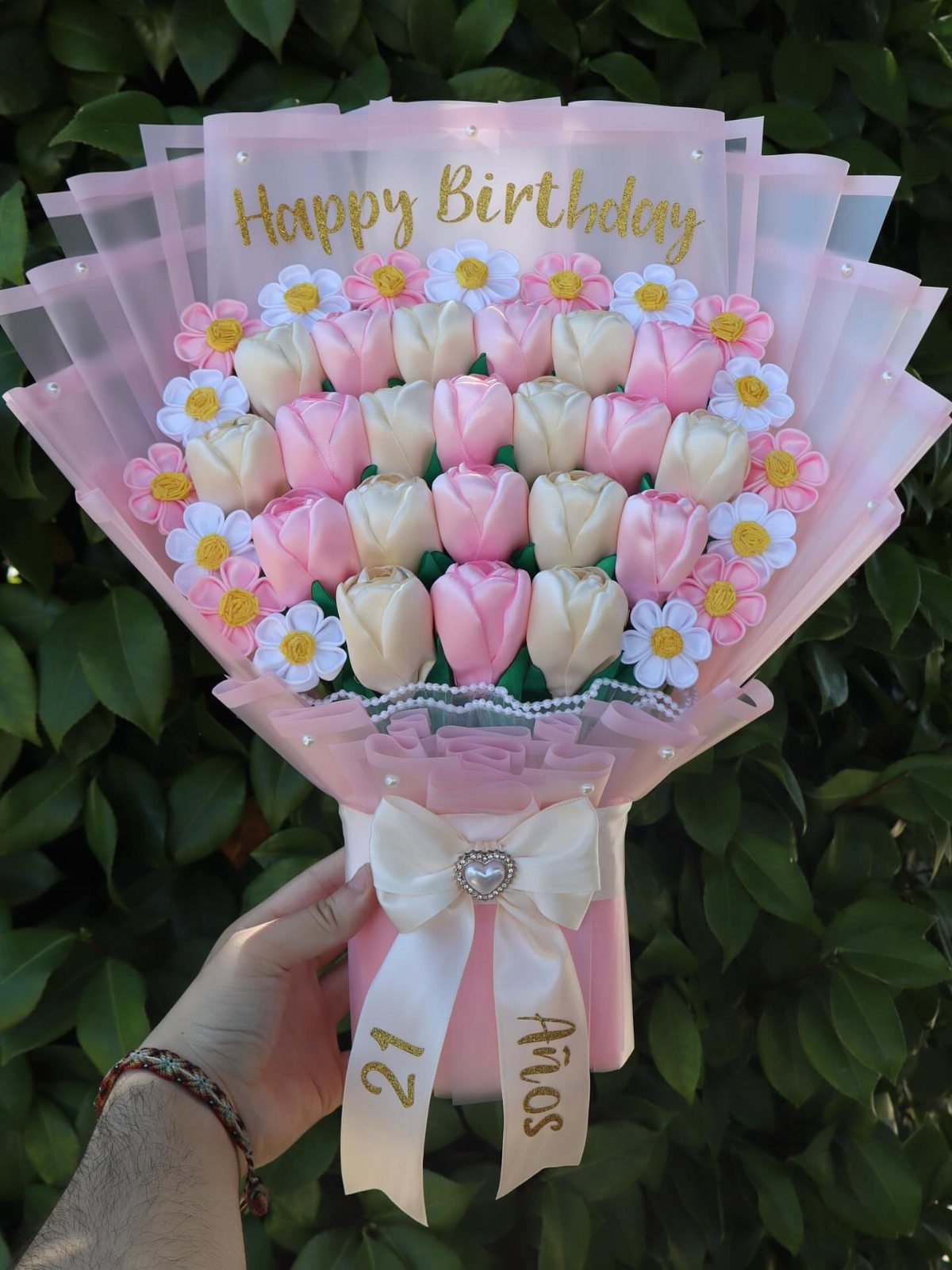Bouquet of pink and white felt tulips and daisies wrapped in pink paper.