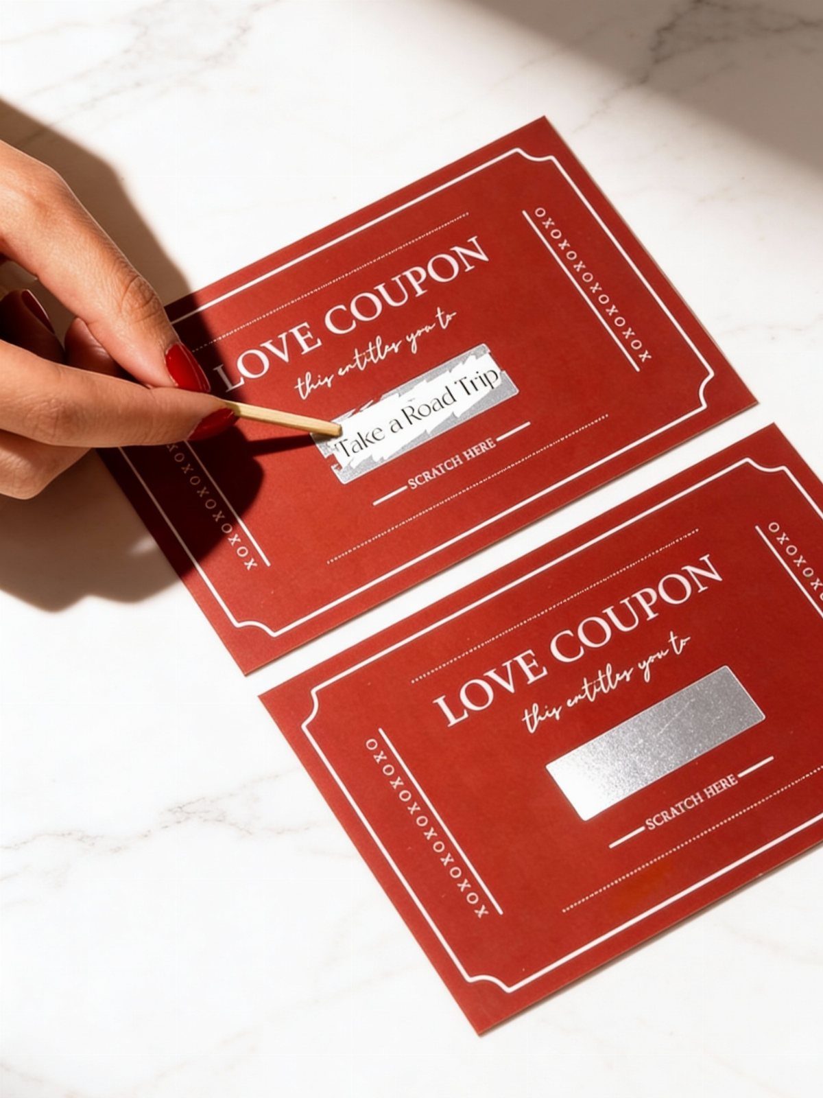 Red love coupons on marble, one being scratched to reveal a road trip favor.