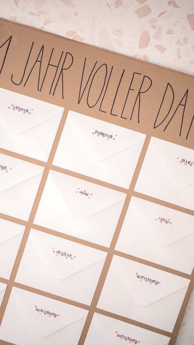 White envelopes with German months written in red on a brown cardboard board.
