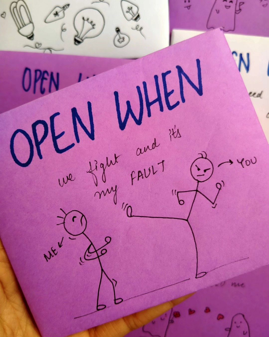 Purple envelope with handwritten Open When text and a funny stick figure drawing.