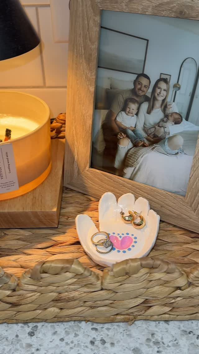 Handprint shaped ceramic jewelry dish with a pink heart holding gold rings and earrings