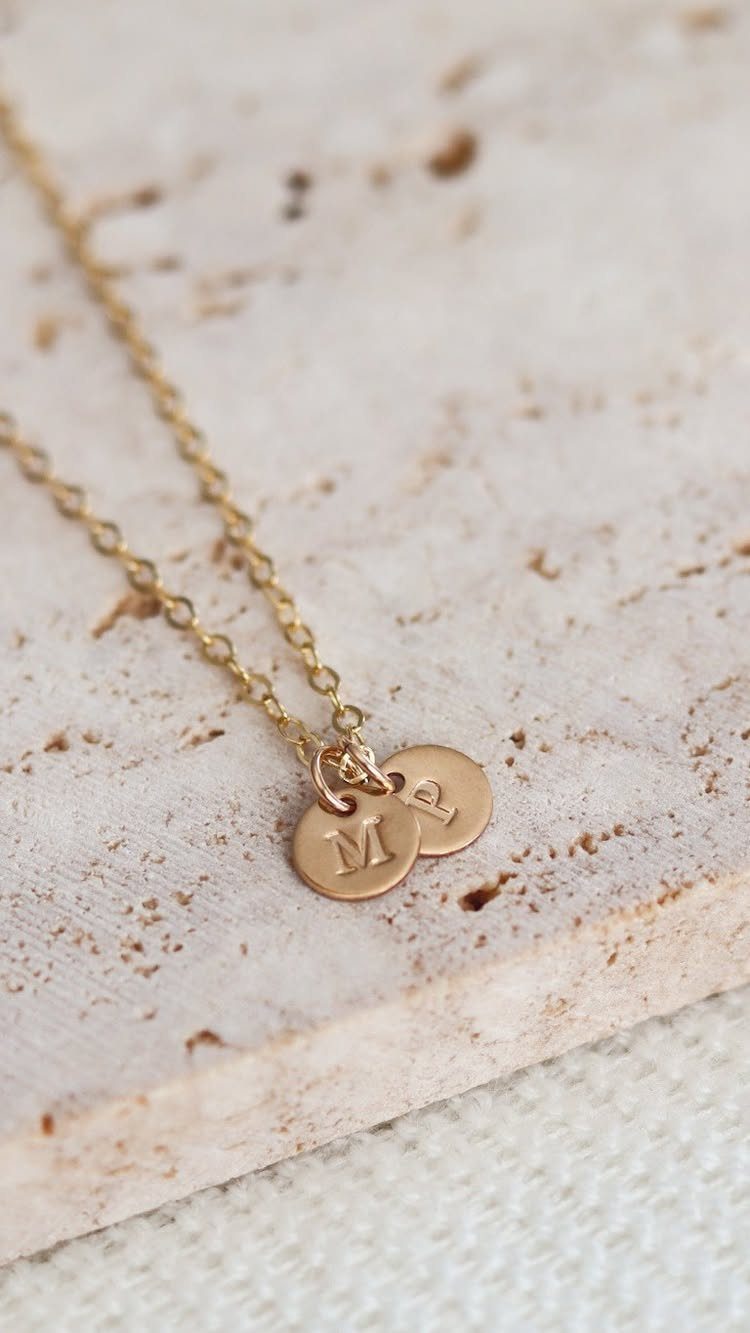 Gold chain necklace with two small circular pendants stamped with letters M and P