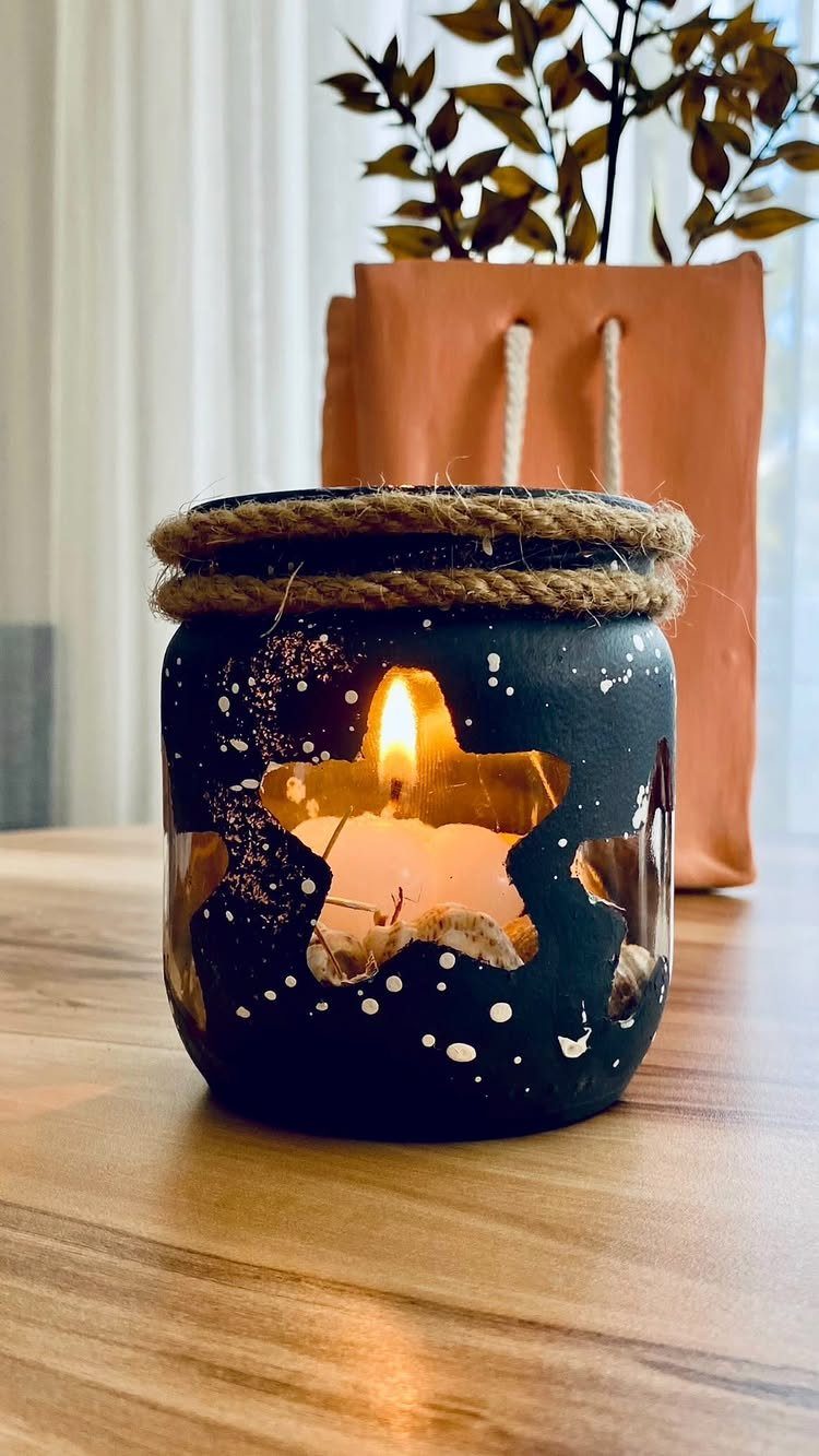 Dark blue painted mason jar candle with star cutouts and twine decoration.