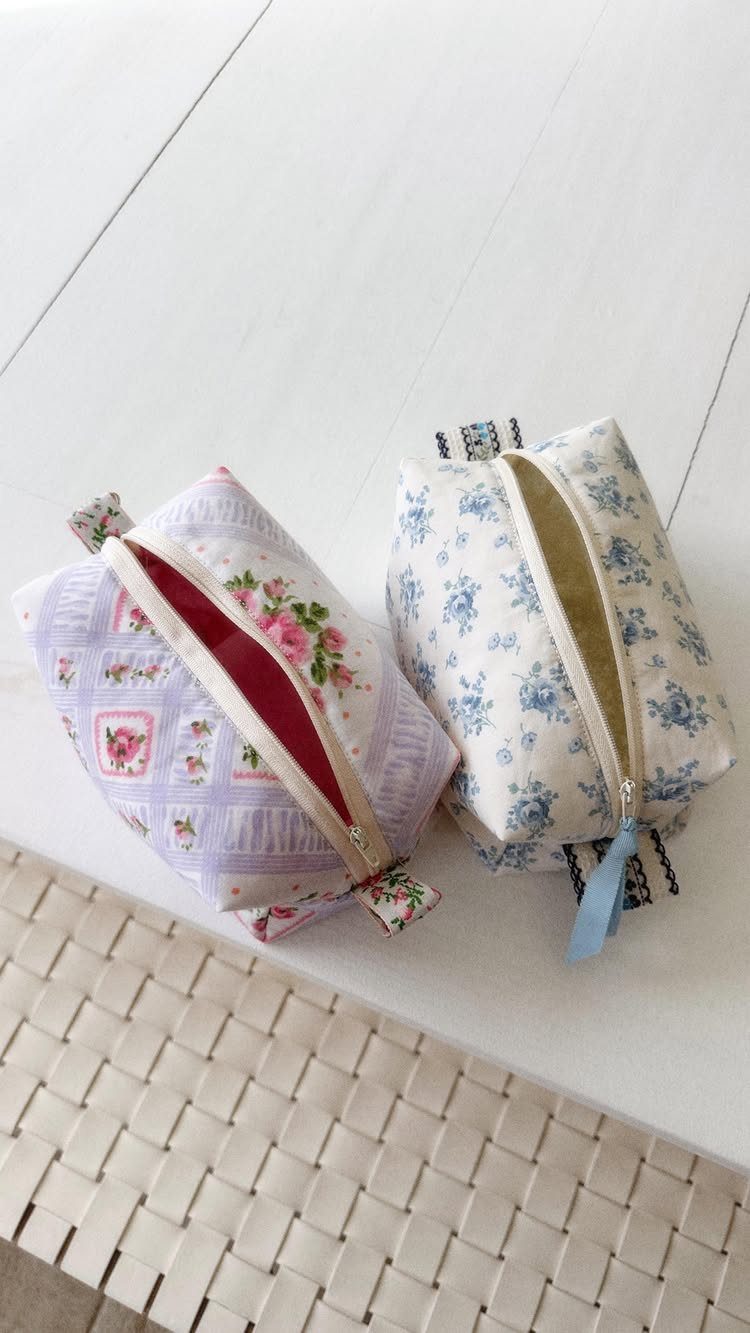 Two floral fabric zipper pouches, one purple and one blue, on white surface.