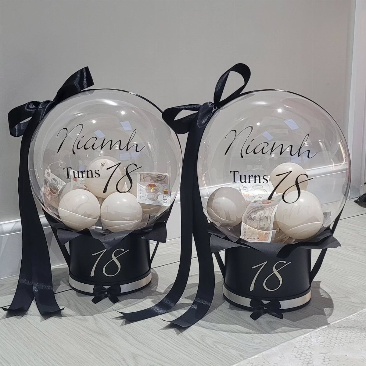 Two 18th birthday gift balloons with white balloons inside black gift boxes.