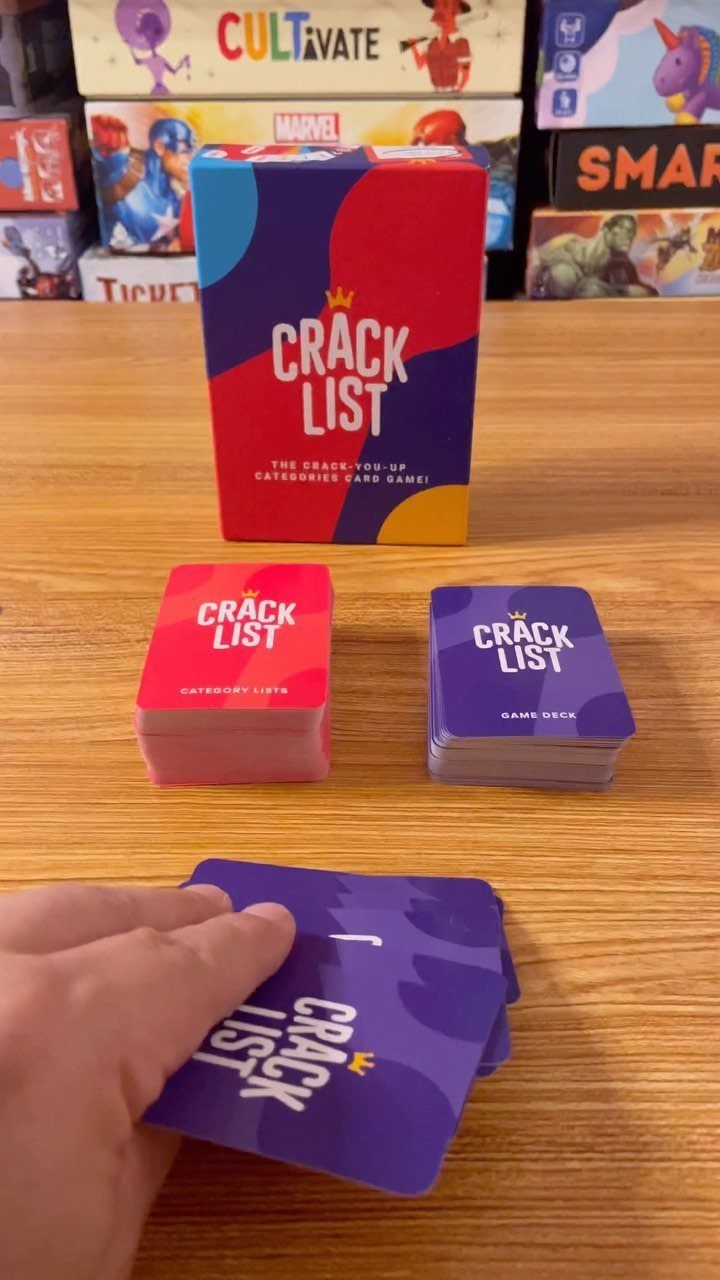 Crack List card game box and cards on a wooden table with hand.