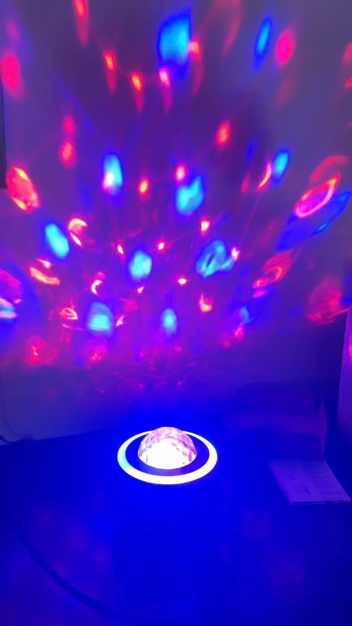 Dome-shaped light projector casting red and blue patterns on a white wall.