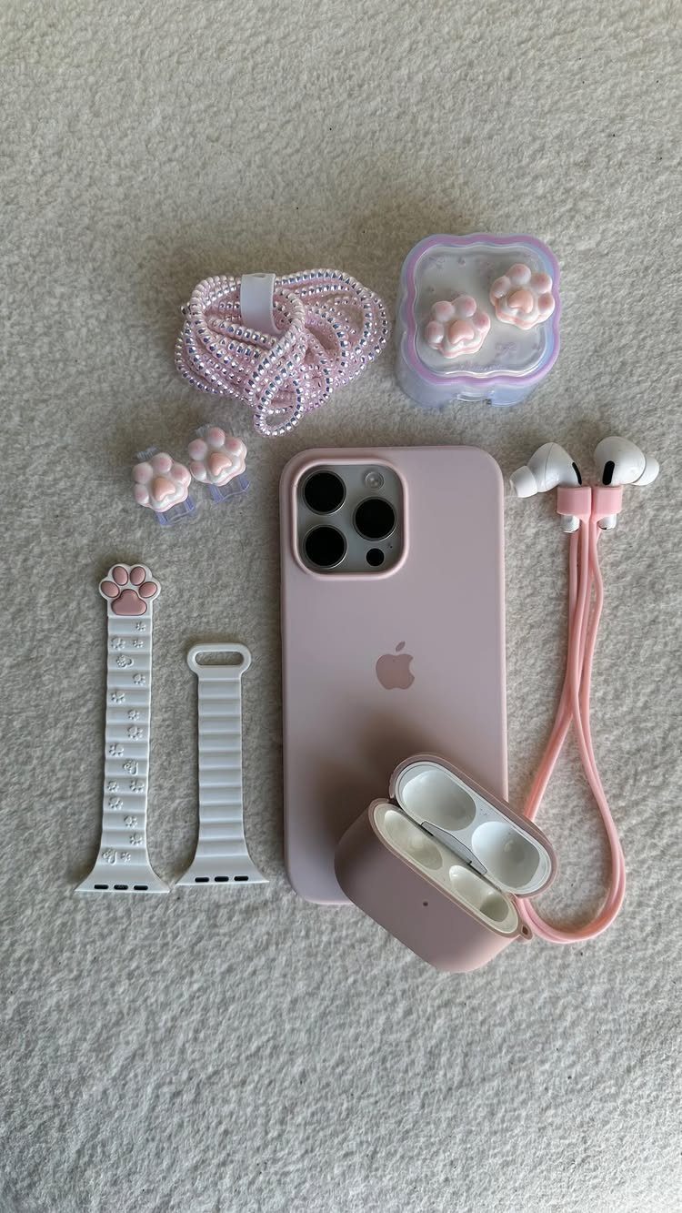 Pink iPhone and matching accessories including earbuds and beaded straps on beige fabric.