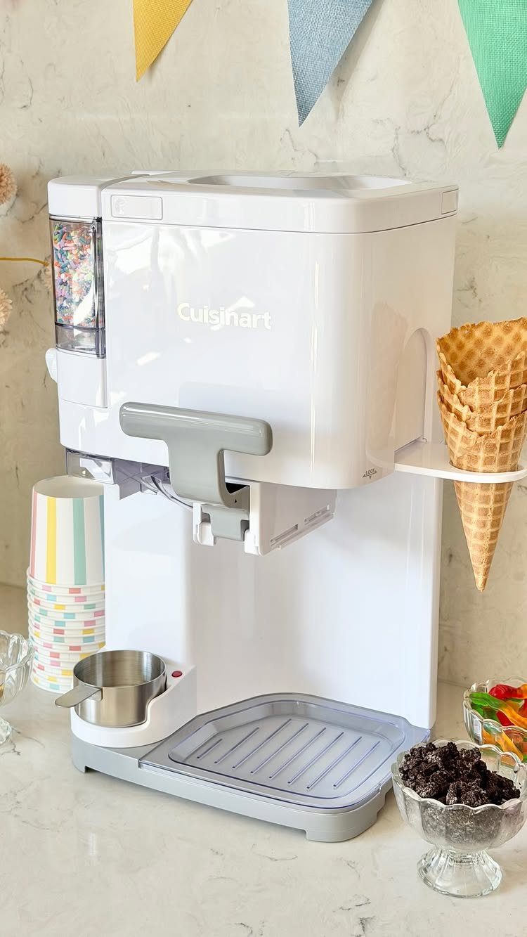 White Cuisinart soft serve ice cream maker with a waffle cone and toppings.