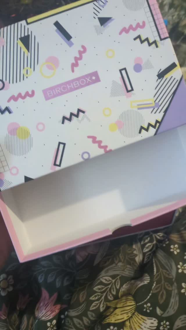 Open Birchbox subscription box with colorful geometric patterns on a floral fabric background