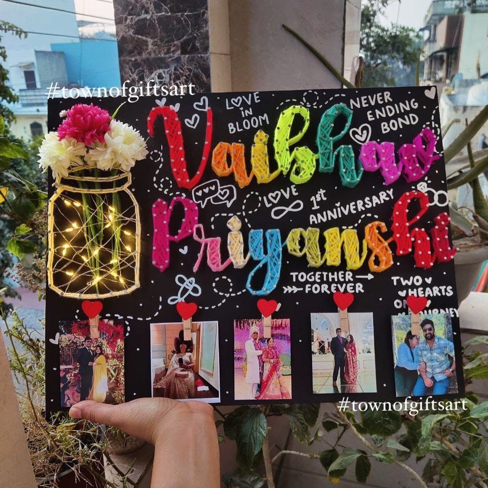 Decorative black anniversary board with colorful yarn names, photos, and a light-up jar.