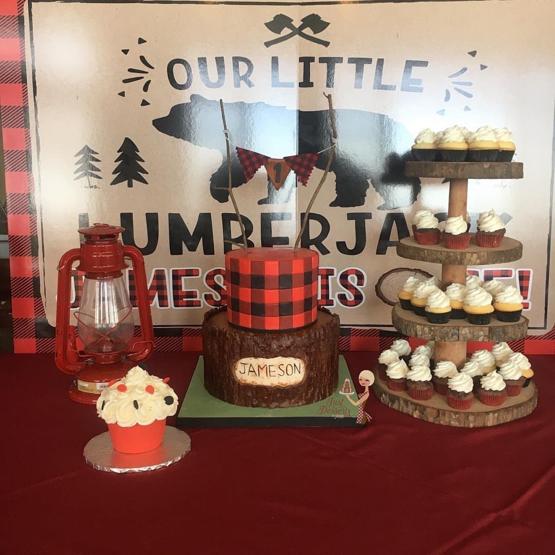 Lumberjack themed cake shaped like a tree stump with red plaid frosting and cupcakes.