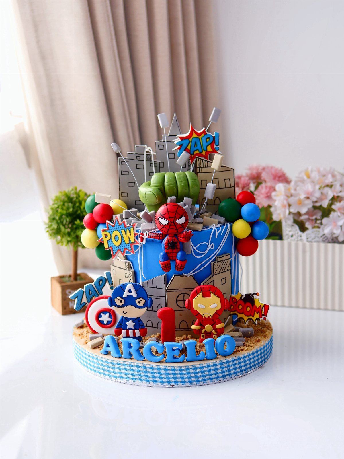 Superhero themed first birthday cake with Spider-Man, Captain America, and Iron Man figures.