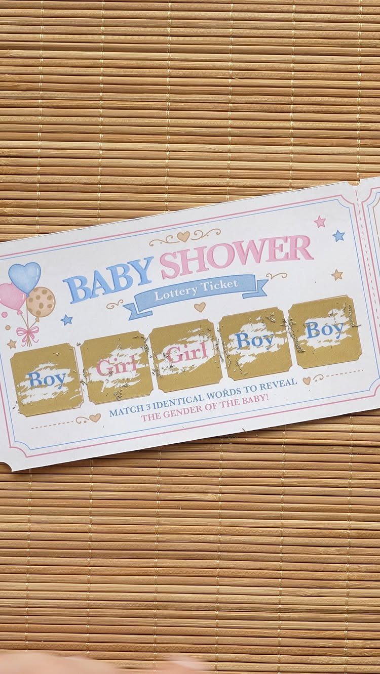 Baby shower scratch card with gold foil squares on a bamboo surface.