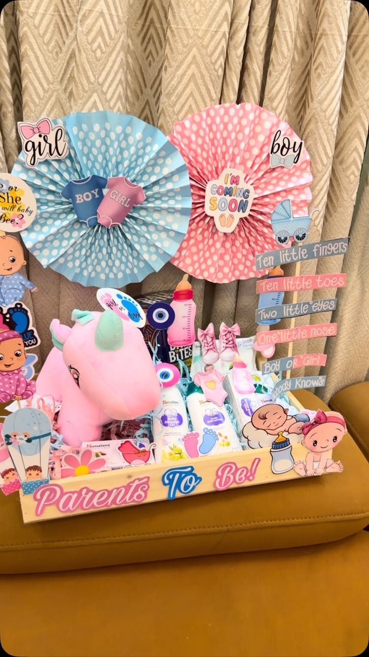 Baby essentials hamper in a wooden tray with pink plush and blue decorations.