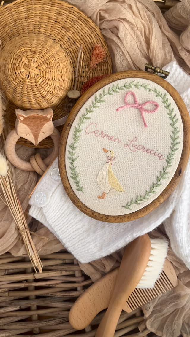 Embroidered baby hoop with name and bird surrounded by wooden baby accessories