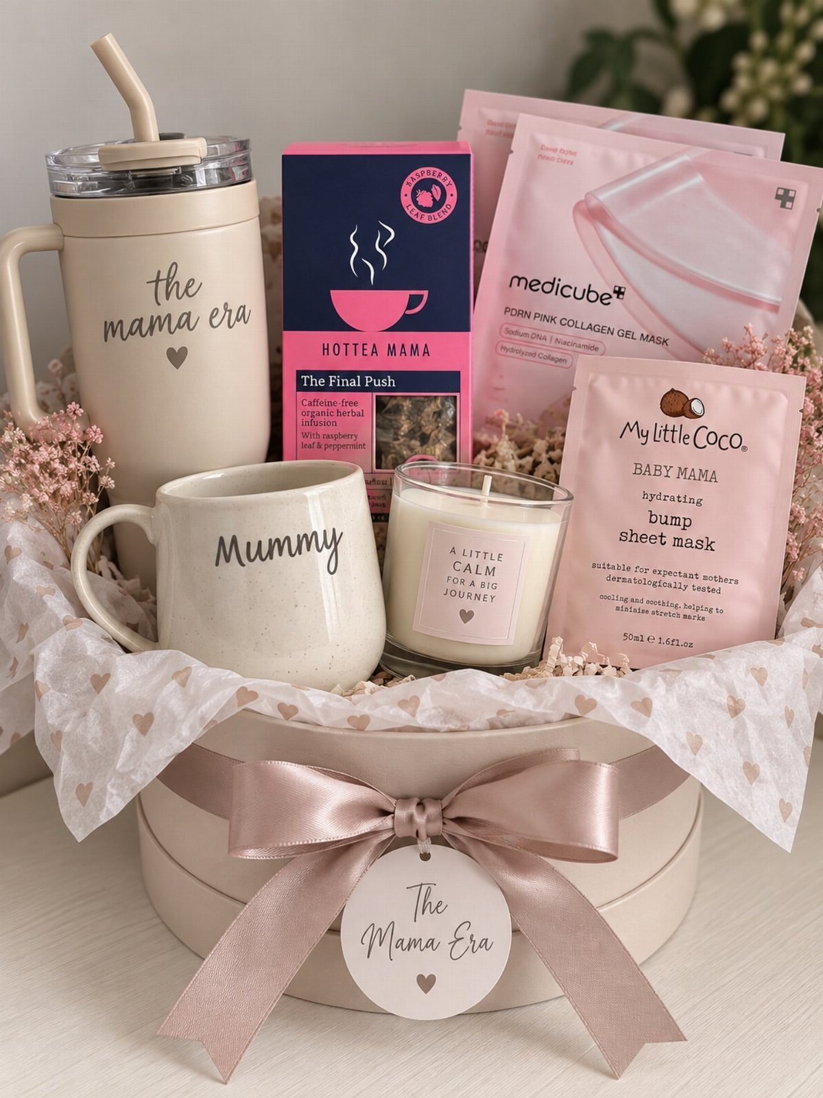 Gift hamper with mugs, candle, and skincare masks in a pink bow box.