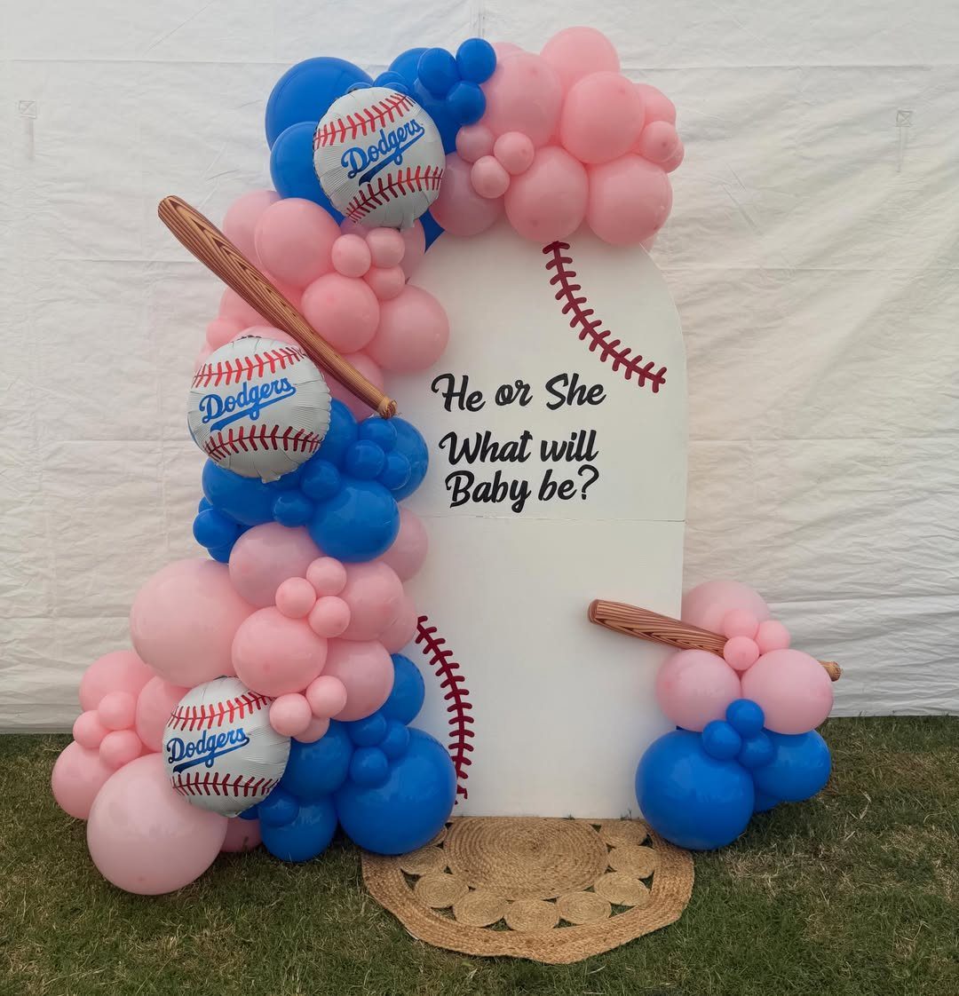 Baseball-themed gender reveal backdrop with pink and blue balloons and Dodgers baseballs.