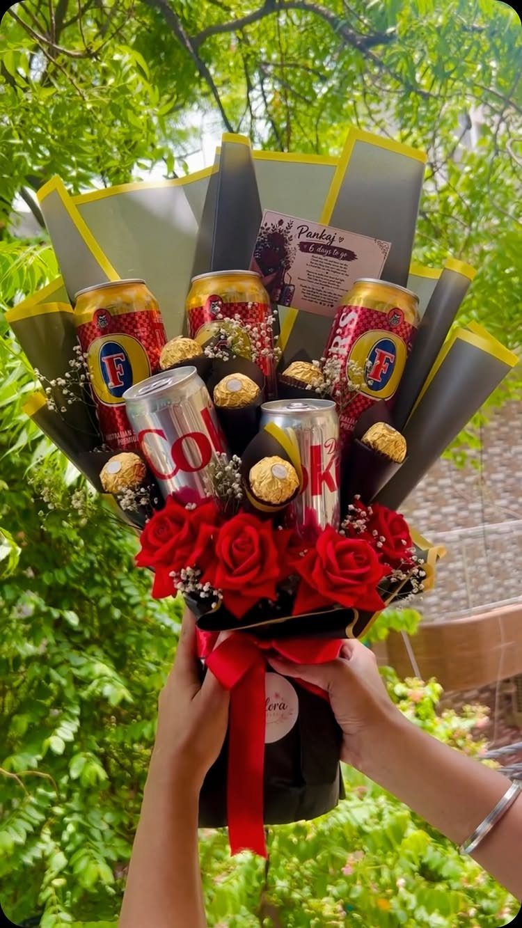 Bouquet of red roses, soda cans, and chocolates wrapped in yellow and black paper.