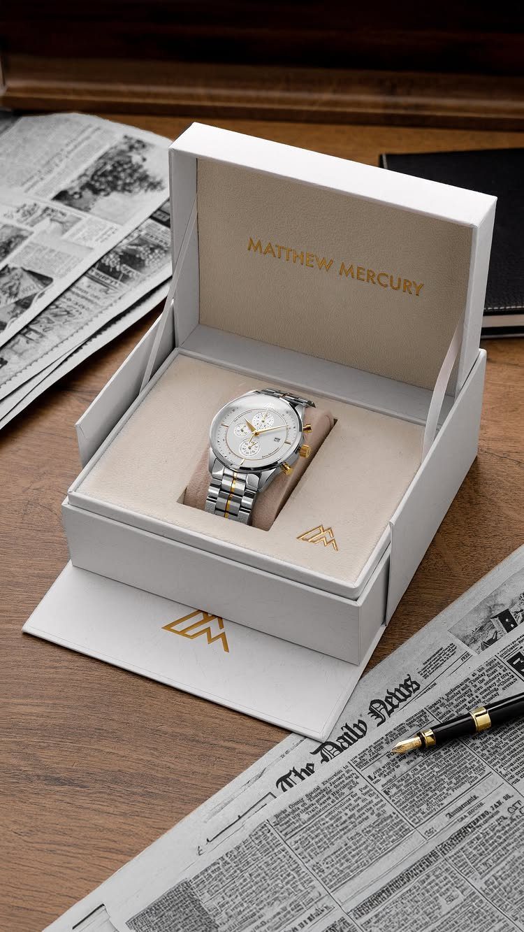 Silver and gold wristwatch in a white gift box on a wooden desk