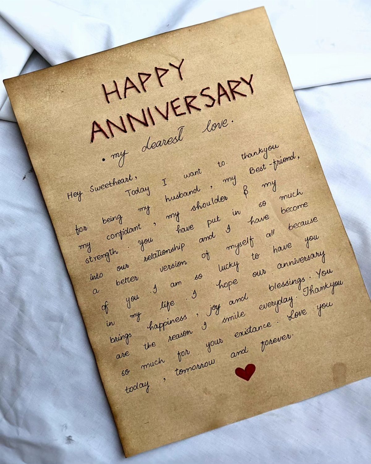 Handwritten anniversary love letter on brown parchment paper with a small red heart.