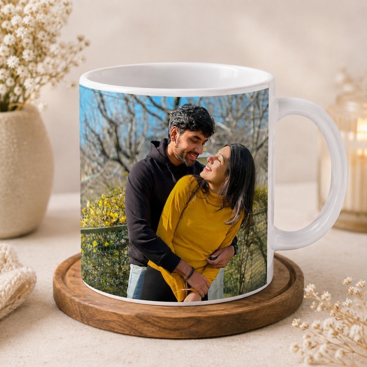 White ceramic mug with a photo of a couple embracing on a wooden coaster