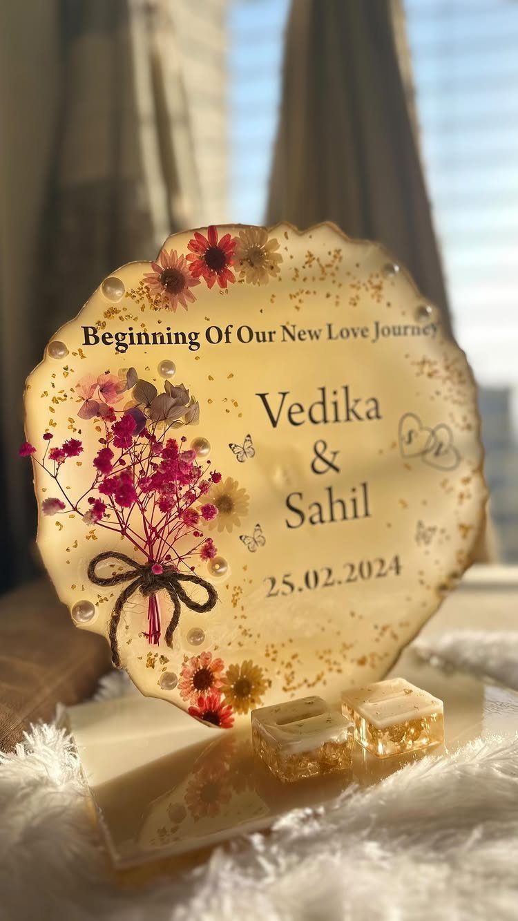 Resin anniversary plaque with dried flowers, names Vedika and Sahil, and a date.