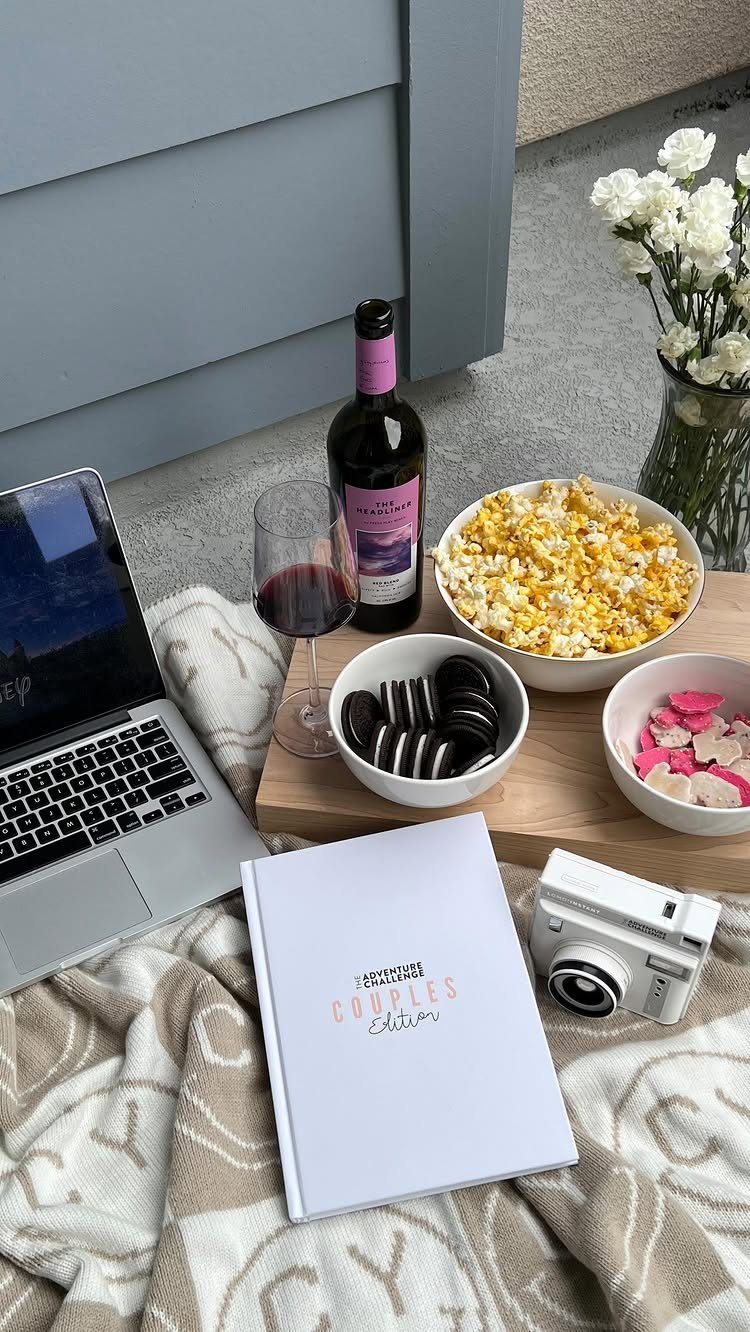 Couples Edition date book with wine, popcorn, and a camera on a blanket.