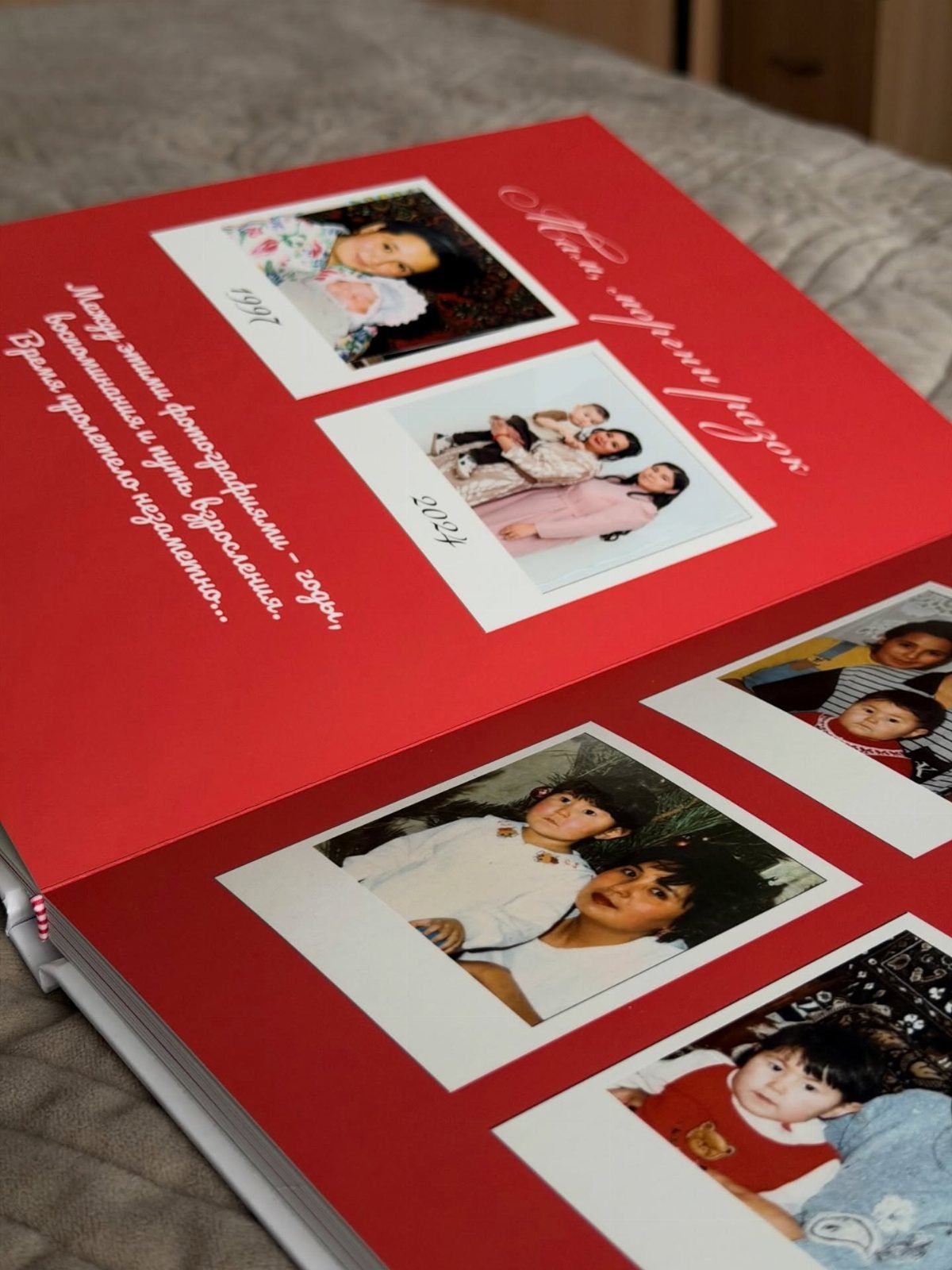 Red photo album open on a grey surface showing family photographs and text.
