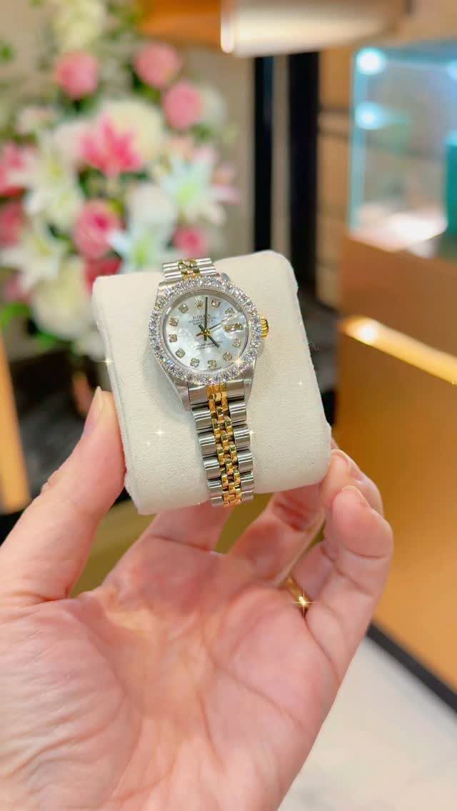 Two-tone silver and gold wristwatch with diamonds on a white jewelry cushion