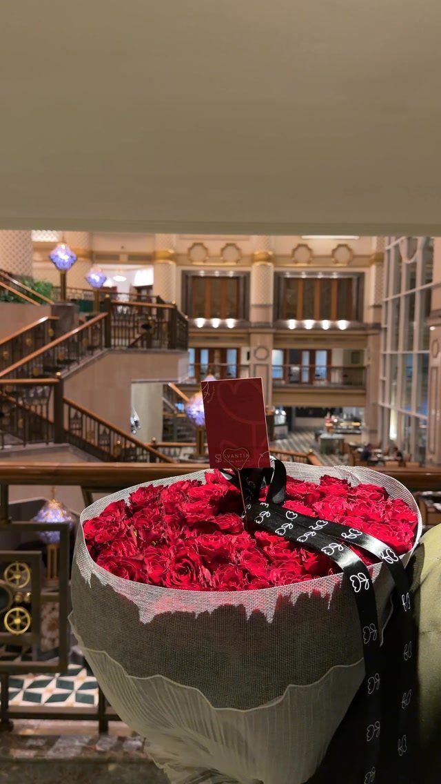 Large bouquet of red roses with a red card in a grand lobby