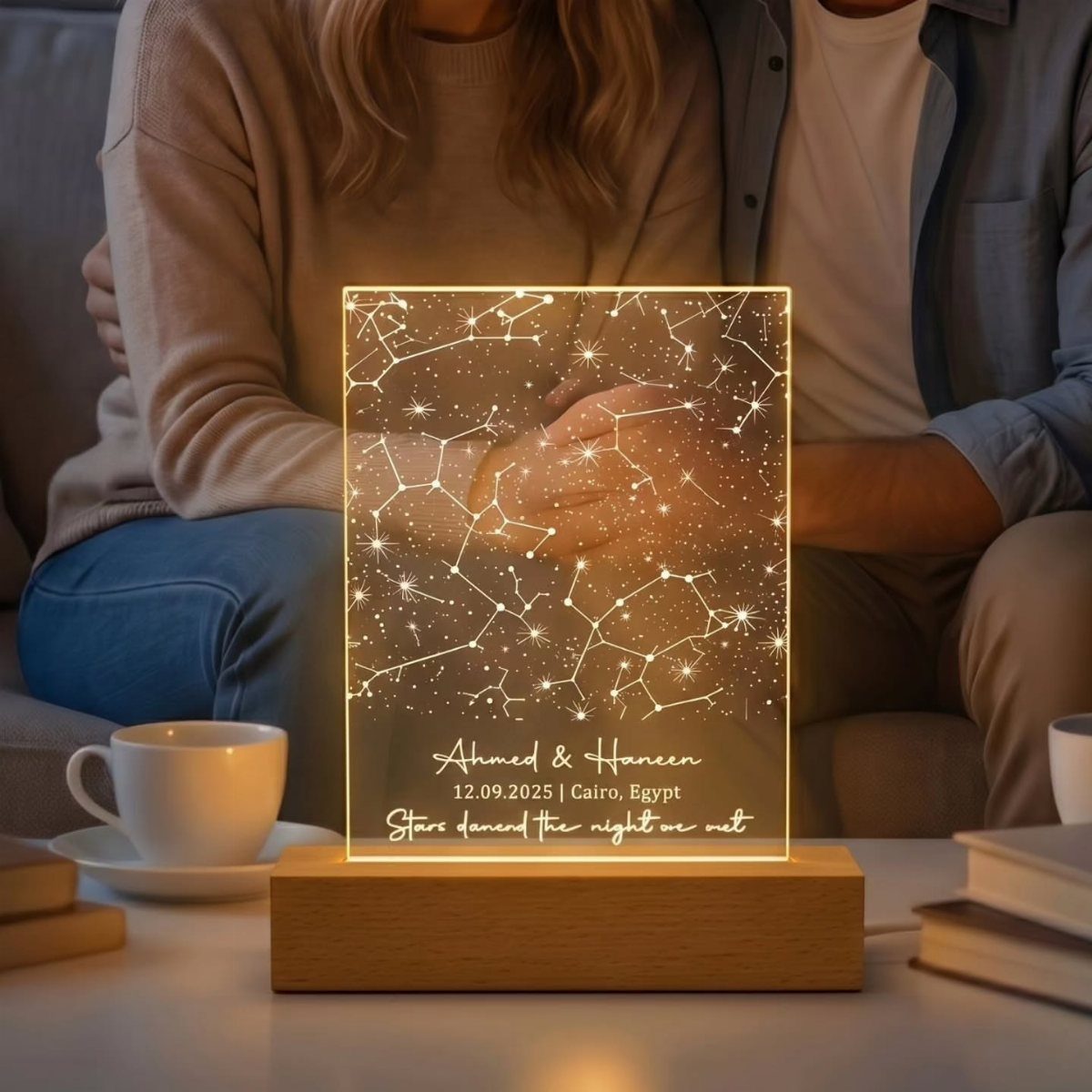 Illuminated acrylic star map plaque on a wooden base with a couple behind it