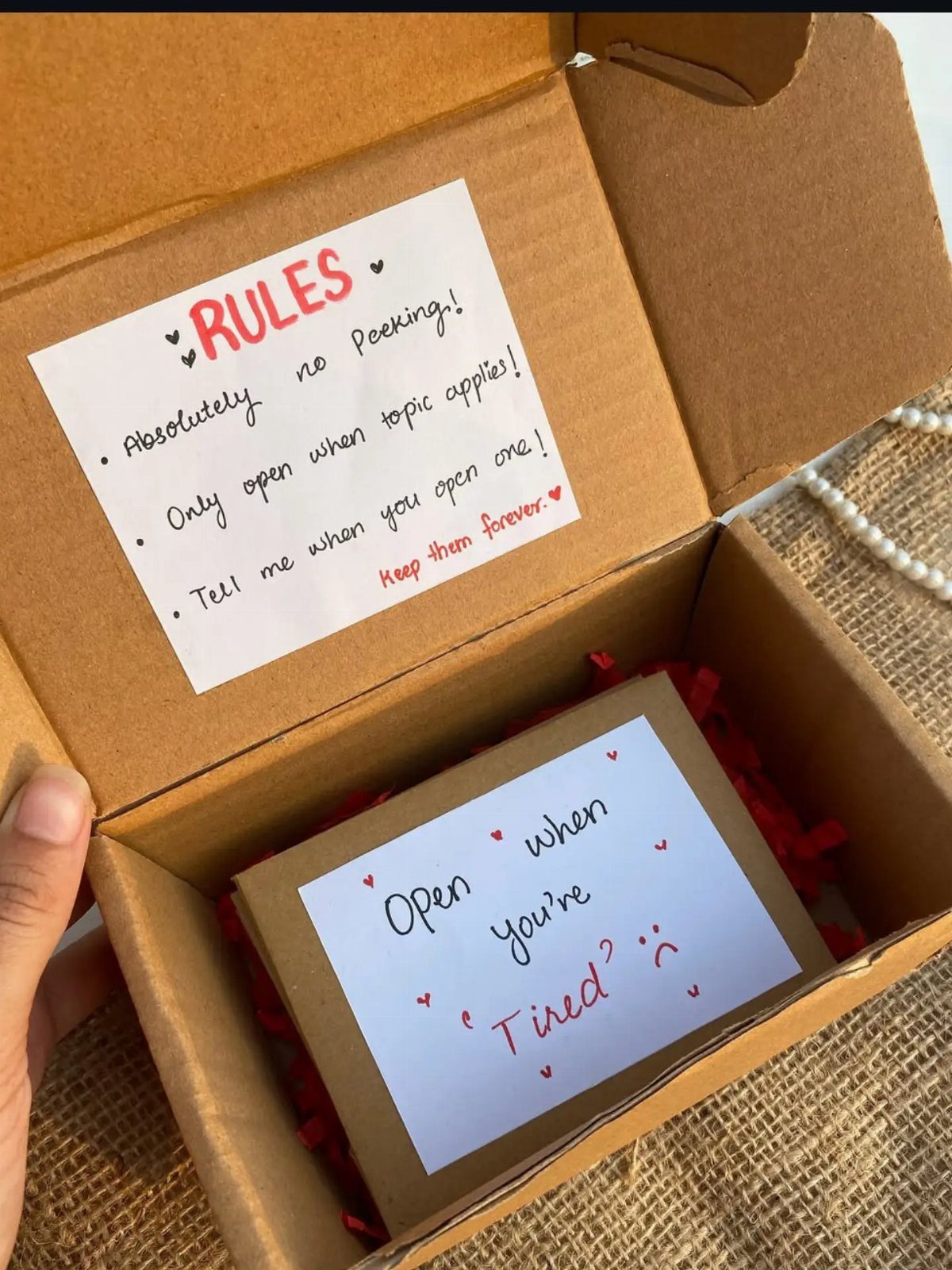 Cardboard gift box with 'Open when' letters and a rules list inside.
