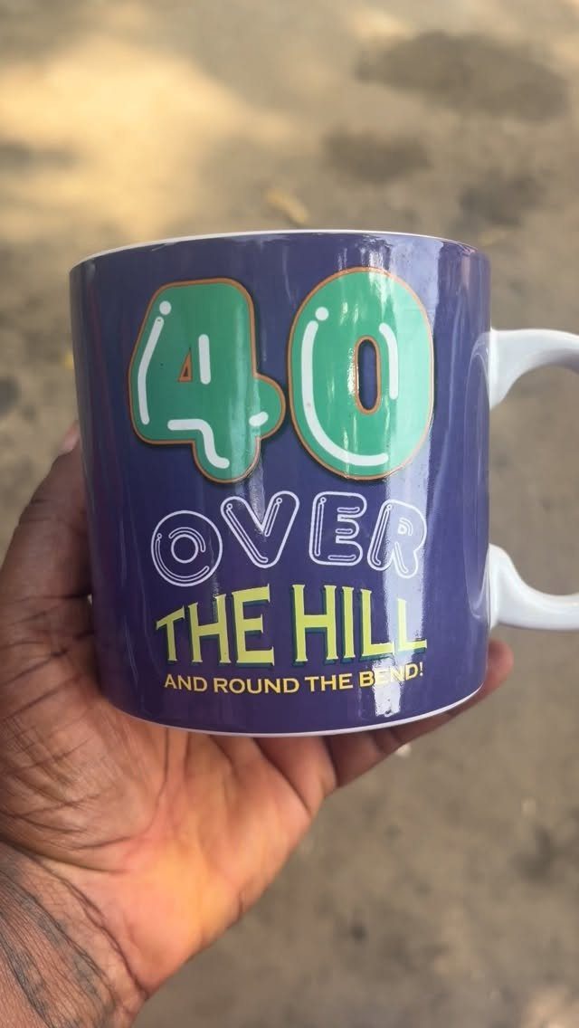 Purple ceramic mug with 40th birthday text held in a person's hand.